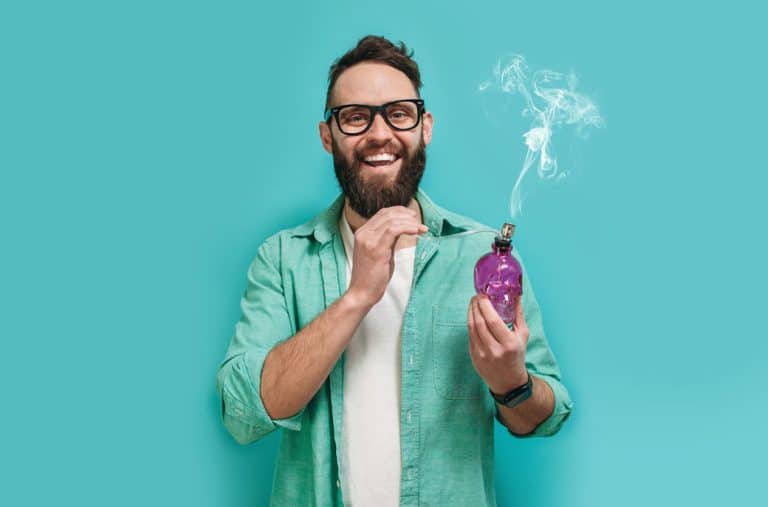 Smiling man holding a purple cannabis vape bottle with smoke, representing recreational use of CBD and THC.